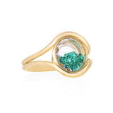 Cascavel Circle Ring Medio Emerald by Moritz Glik in 18k yellow gold with 0.42ct of emeralds enclosed in a circle-shaped Kaleidoscope Shaker on white background, facing right