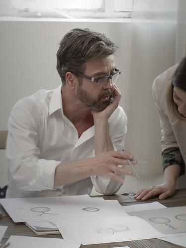 Moritz Glik sitting on a chair by a desk showing his drawing to a woman