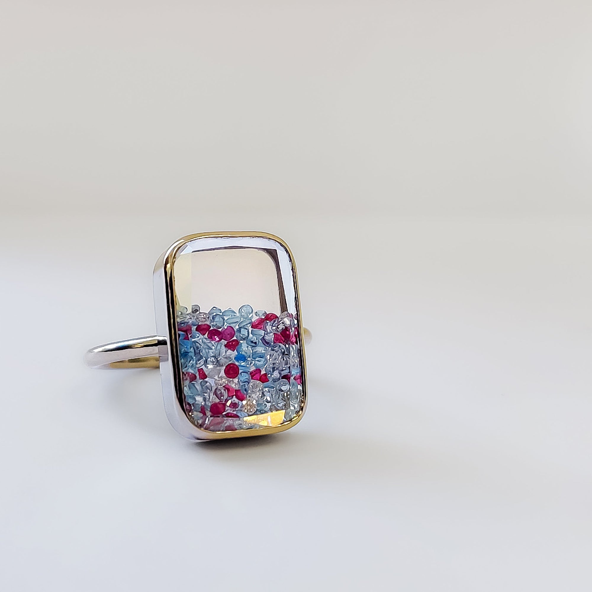 Ten Fourteen Ring by Moritz Glik with colorful gemstones on a light gray background